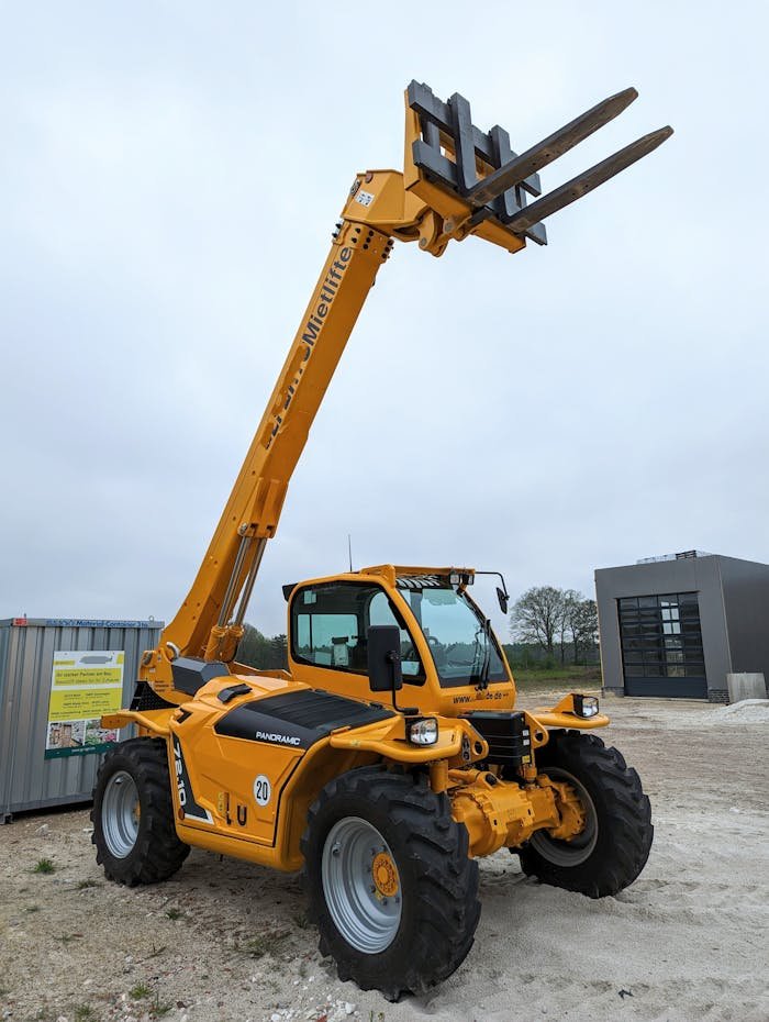 Yellow telescopic forklift lifting arm on a cloudy day at a construction site in Meppen, Germany.
